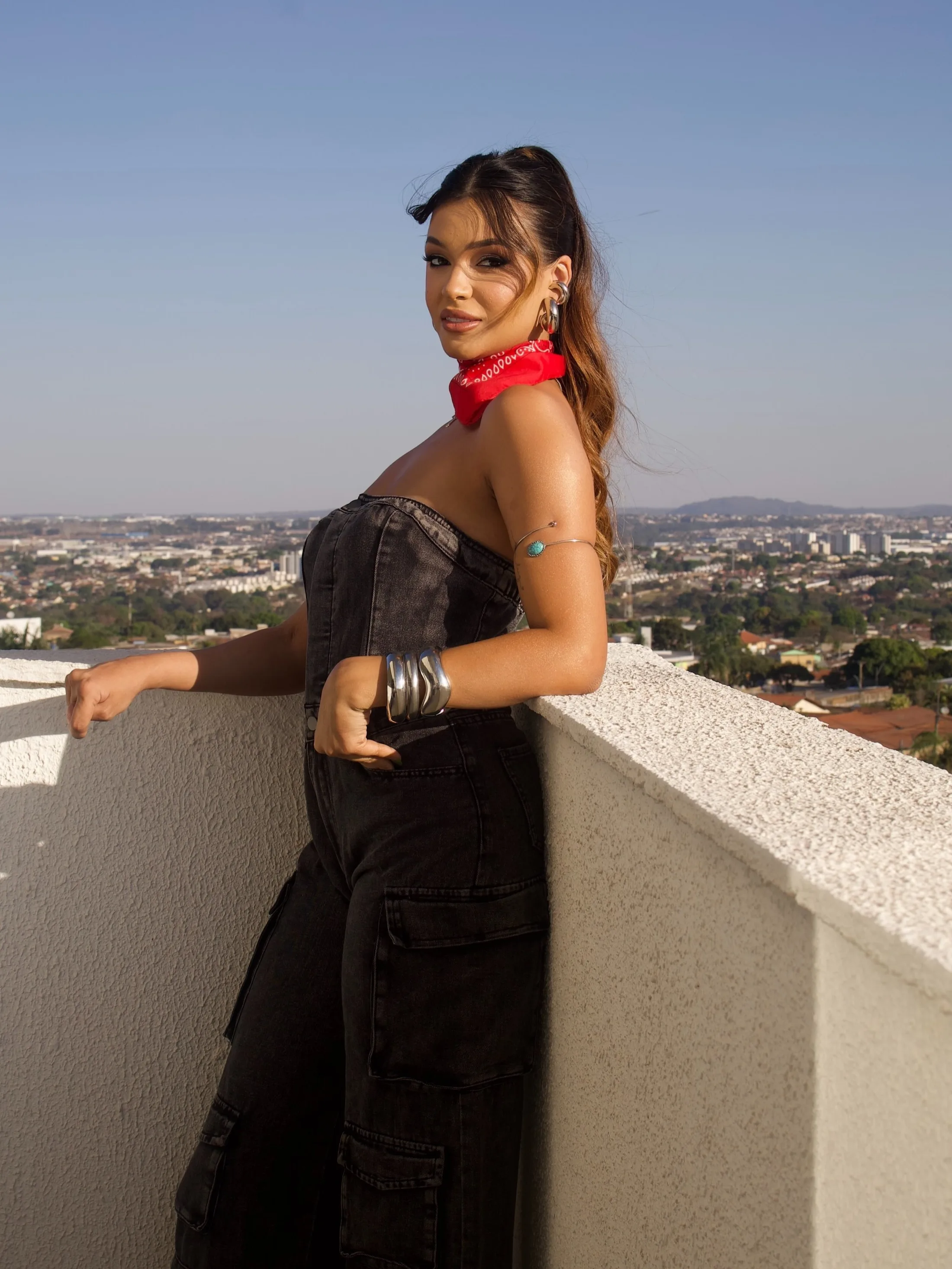 Mulher de roupa jeans preta e lenço vermelho em um terraço